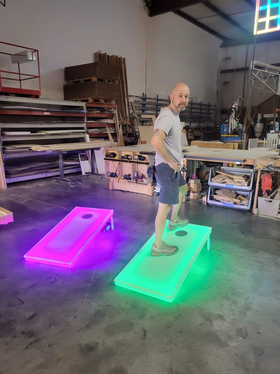 Andy Lakatos stands near his lighted cornhole game.