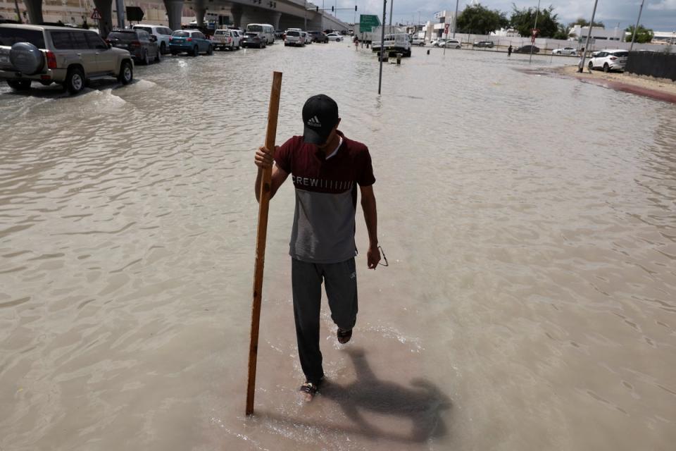 A person walks surrounded by flood water caused by heavy rains, in Dubai, United Arab Emirates (REUTERS)