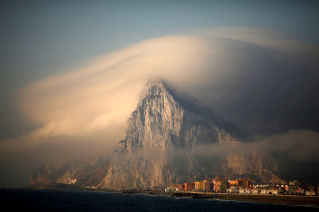 FILE PHOTO: A cloud partially covers the tip of the Rock of the British territory of Gibraltar at sunrise from La Atunara port before Spanish fishermen sail in their fishing boats with their relatives to take part in a protest at an area of the sea where an artificial reef was built by Gibraltar using concrete blocks, in Algeciras bay, La Linea de la Concepcion in southern Spain August 18, 2013. REUTERS/Jon Nazca/File Photo