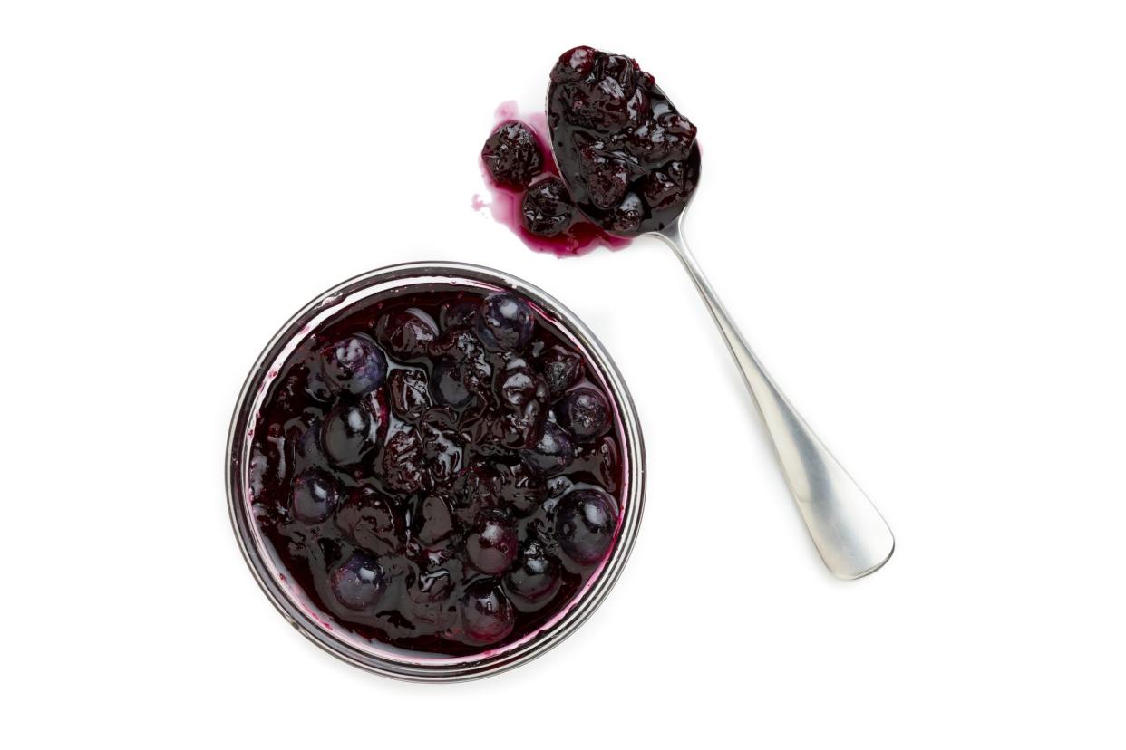 Bowl of fresh Blueberry compote and spoon with messy spill.