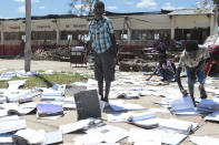 Schoolchildren pick up books that were left to dry in the sun after their school was damaged by Cyclone Idai, in Inchope Mozambique, Monday March 25, 2019. Cyclone Idai's death toll has risen above 750 in the three southern African countries hit 10 days ago by the storm, as workers rush to restore electricity, water and try to prevent outbreak of cholera. (AP Photo/Tsvangirayi Mukwazhi)