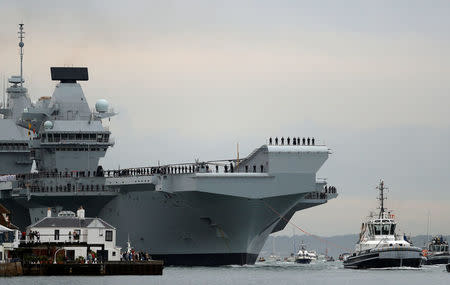 The Royal Navy's new aircraft carrier, HMS Queen Elizabeth, is towed by tugs as it arrives at Portsmouth Naval base, its new home port, in Portsmouth, Britain August 16, 2017. REUTERS/Peter Nicholls