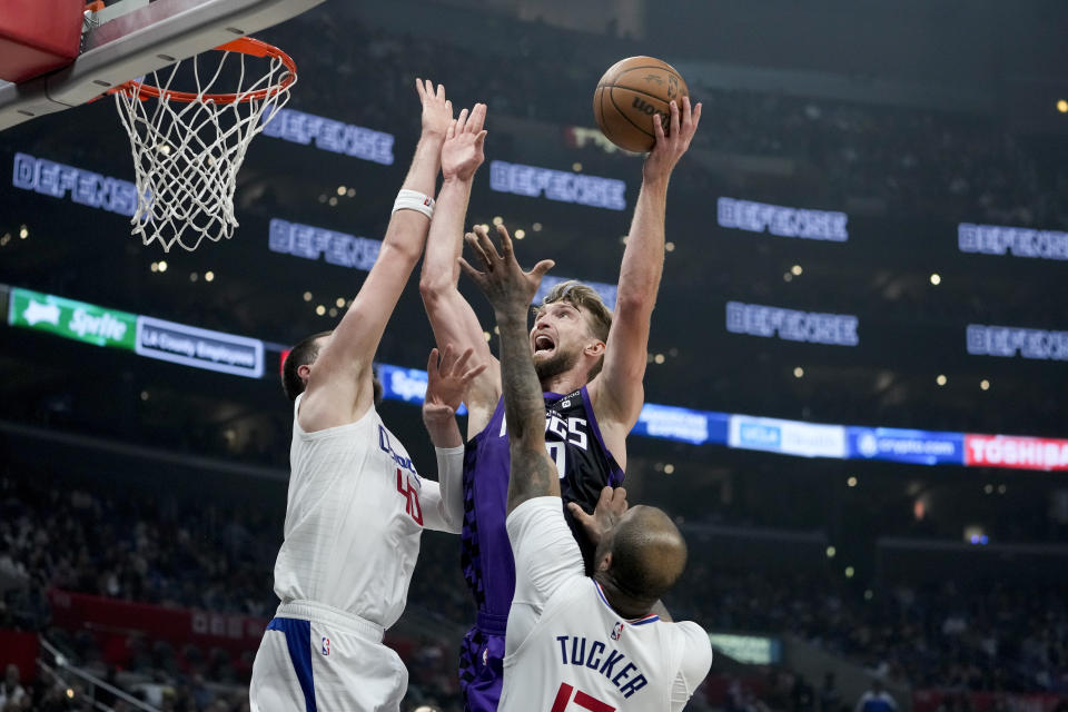 Sacramento Kings forward Domantas Sabonis, center, shoots against Los Angeles Clippers center Ivica Zubac, left, and forward P.J. Tucker during the first half of an NBA basketball game, Sunday, Feb. 25, 2024, in Los Angeles. (AP Photo/Ryan Sun)