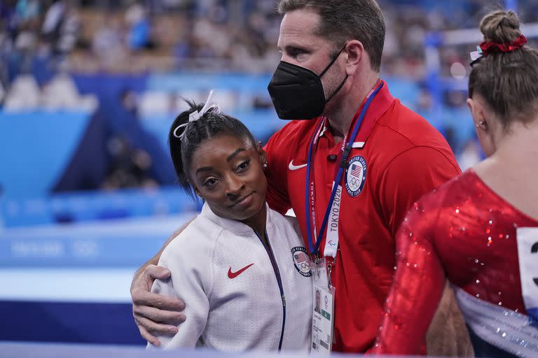 El entrenador Laurent Landi consuela a Biles, luego de que se retirara del equipo 