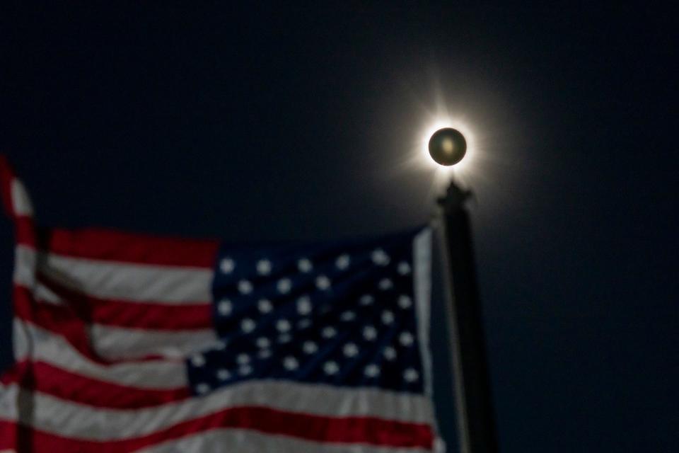 A total solar eclipse is seen beside a waving American flag in Houlton, Maine, the easternmost city in the United States in the path of the eclipse.