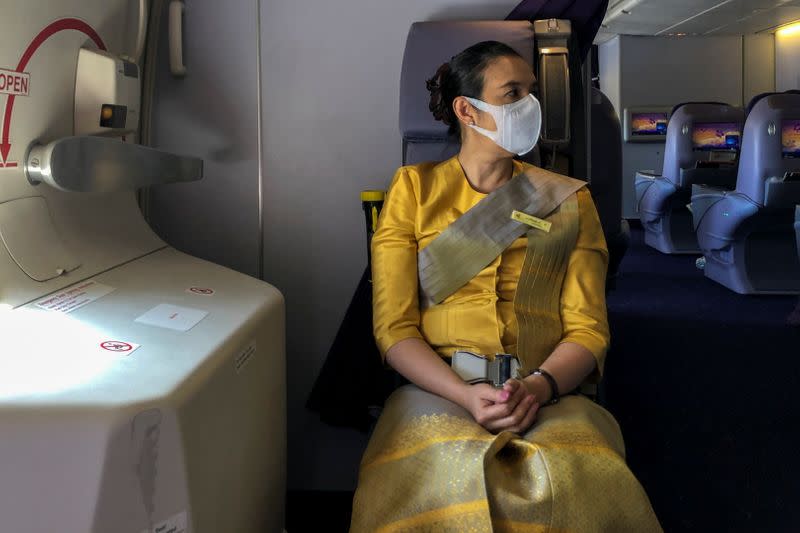 A flight attendant wearing a protective face mask is pictured during a flight from Sydney to Bangkok