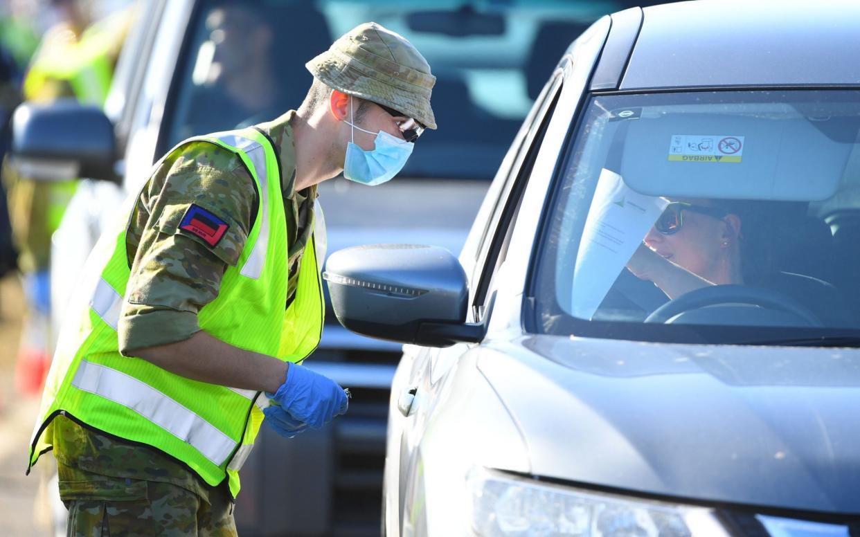 Australian Defense Force personnel work at a vehicle checkpoint along the Princes Freeway outside of Melbourne, Australia - Shutterstock 