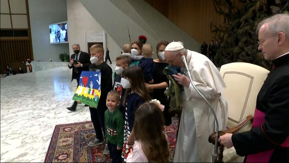 Pope Francis kisses the Ukrainian flag.