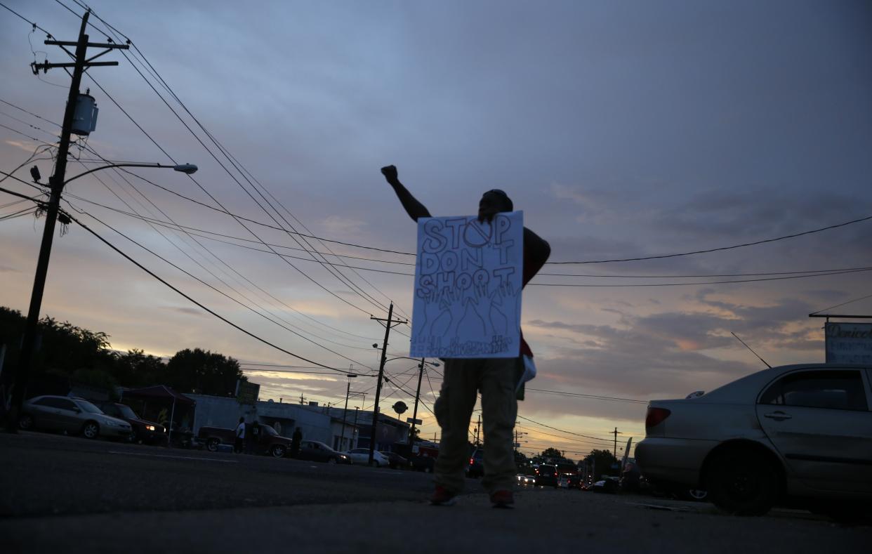 Troy Holliday, of Baton Rouge, holds a sign and gestures to passing motorists in honor of  Alton Sterling, outside the Triple S Food Mart in Baton Rouge, La., Monday, July 11, 2016. Sterling was shot and killed last Tuesday by Baton Rouge police while selling CD's outside the convenience store. (AP Photo/Gerald Herbert)