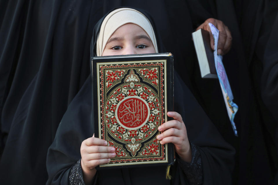 A supporter of the Shiite cleric Muqtada al-Sadr holds the Quran, the Muslim holy book, in response to the burning of a copy of the Quran in Sweden, during a rally in Basra, Iraq, Sunday, July 2, 2023. (AP Photo/Nabil al-Jurani)