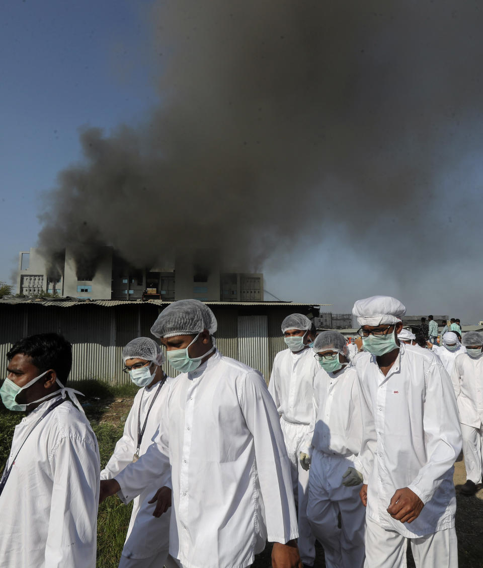 Employees leave as smoke rises from a fire at Serum Institute of India, the world's largest vaccine maker that is manufacturing the AstraZeneca/Oxford University vaccine for the coronavirus, in Pune, India, Thursday, Jan. 21, 2021. (AP Photo/Rafiq Maqbool)