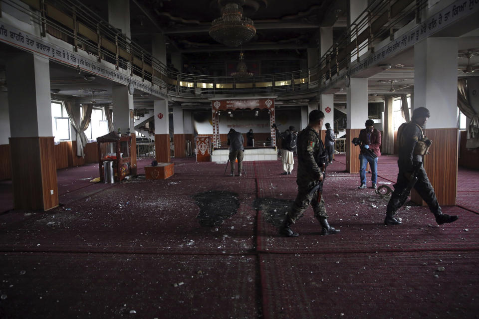 FILE- in this Wednesday, March 25, 2020 file photo, Afghan security personnel and journalists inspect the inside a Sikh house of worship, after an attack in Kabul, Afghanistan. Afghanistan’s dwindling community of Sikhs and Hindus is shrinking to its lowest levels. With growing threats from the local Islamic State affiliate, many are choosing to leave the country of their birth to escape the insecurity and a once-thriving community of as many as 250,000 members now counts fewer than 700. (AP Photo/Rahmat Gul, file)