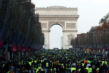 Protesters wearing yellow vests walk on the Champs-Elysees Avenue with the Arc de Triomphe in the background during a national day of protest by the "yellow vests" movement in Paris, France, December 8, 2018. REUTERS/Christian Hartmann