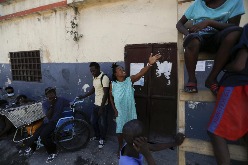 A woman orders her son to come down from a ladder at a shelter for displaced Haitians, in Port-au-Prince, Haiti, Saturday, July 10, 2021, three days after Haitian President Jovenel Moise was assassinated in his home. The displaced Haitians were forced to flee their community where they had settled after the 2010 earthquake, after armed gangs set their homes on fire in late June. (AP Photo/Fernando Llano)