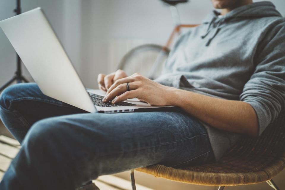 Man working at home with laptop open on lap