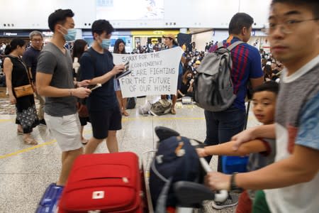 Anti-extradition bill protesters hold up a sign for arriving travellers during a protest at the arrival hall of Hong Kong International Airport in Hong Kong