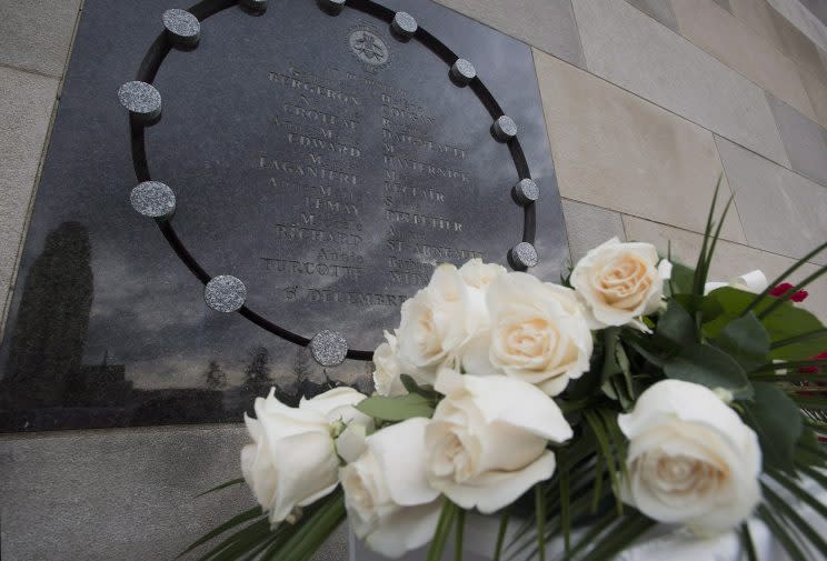 Flowers sit next to a plaque at the École Polytechnique in Montreal in 2013. The plaque commemorates the 14 women who died at the hands of a gunman at the university on Dec. 6, 1989. Photo from The Canadian Press