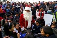 Migrant children surround a volunteer dressed as Father Christmas during a Christmas gathering organized by local relief organization "Die Johanniter" at the refugee camp in Hanau, Germany, December 24, 2015. REUTERS/Kai Pfaffenbach/Files