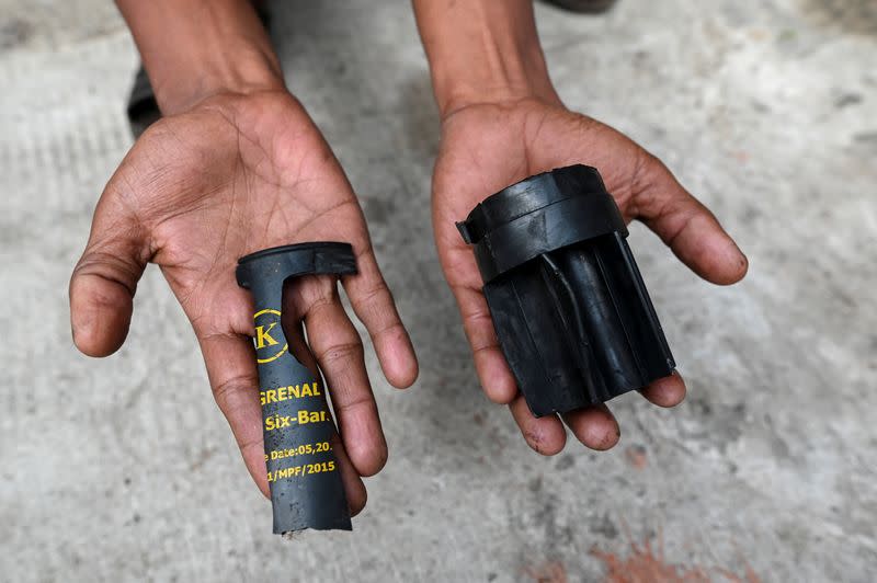 A man holds parts of a teargas grenade that riot police officers used to disperse a crowd that held a protest the night before in Yangon's Tamwe neighborhood