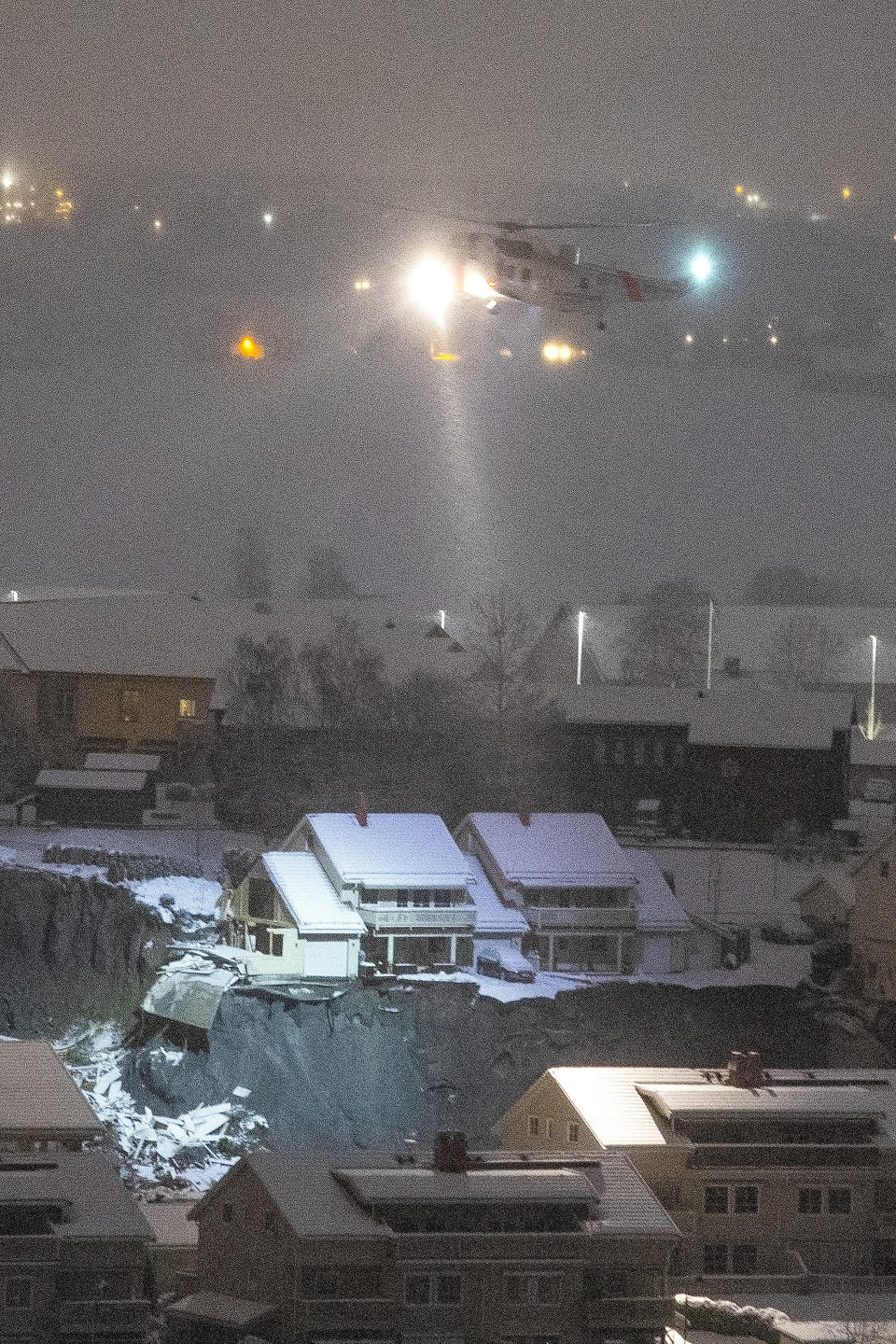 A rescue helicopter files over the site of a landslide in Ask, northeast of Oslo, early Thursday morning Dec. 31, 2020. A landslide smashed into a residential area near the Norwegian capital Wednesday. (Terje Bendiksby/NTB via AP)