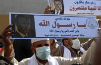 Islamic scholars hold defaced pictures of French President Emmanuel Macron during a protest against the publishing of caricatures of the Prophet Muhammad they deem blasphemous, in front of the French Cultural center in Gaza City, Monday, Oct. 26, 2020. Arabic reads: "Despite Macron's malice, we rise up to our Prophet" and "I sacrifice myself, my father and mother for you Prophet." (AP Photo/Adel Hana)