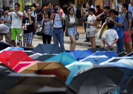 People stand near an art work made with umbrellas as protesters continue blocking a commercial area of Causeway Bay in Hong Kong, October 11, 2014. REUTERS/Carlos Barria