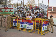 Devotees stand behind barricades as they wait for Naga Sadhu or Naked Hindu holy men to arrive for Shahi snan or a Royal bath during Kumbh mela, in Haridwar in the Indian state of Uttarakhand, Monday, April 12, 2021. As states across India are declaring some version of a lockdown to battle rising Covid cases as part of a nationwide second-wave, thousands of pilgrims are gathering on the banks of the river Ganga for the Hindu festival Kumbh Mela. The faithful believe that a dip in the waters of the Ganga will absolve them of their sins and deliver them from the cycle of birth and death. (AP Photo/Karma Sonam)