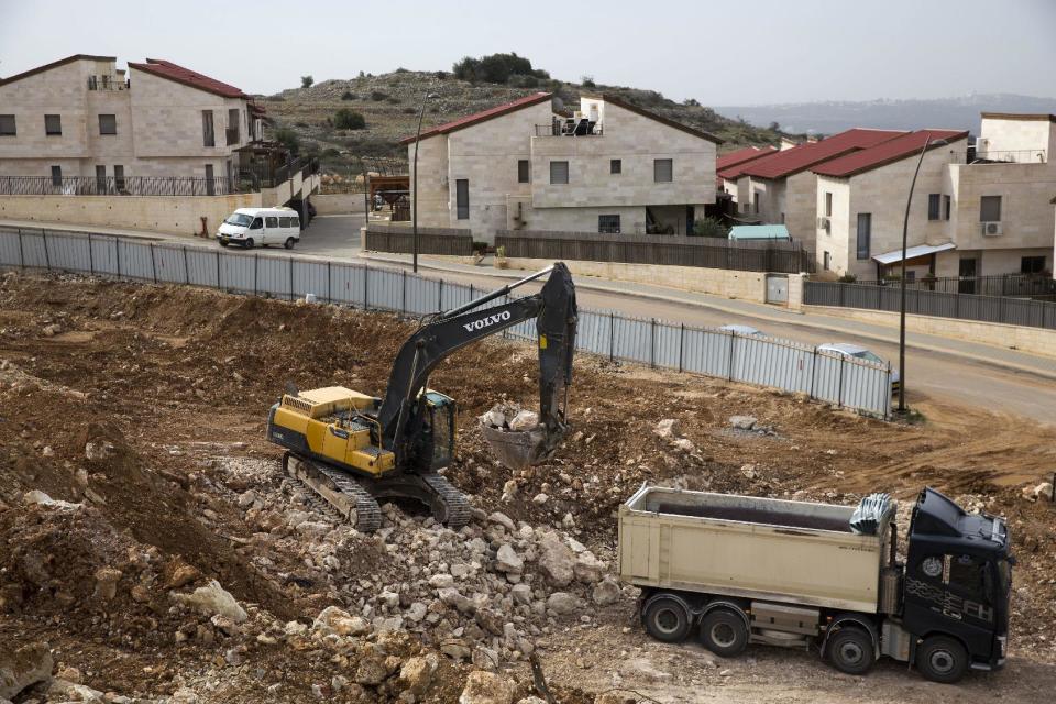 FILE - In this Wednesday, Jan. 25, 2017, file photo, heavy machinery work at a construction site in the West Bank Jewish settlement of Ariel. Israel’s prime minister is moving ahead with a contentious law that would legalize dozens of settlement outposts in the West Bank, despite questions about the bill’s legality and a warning from the White House that settlement construction “may not be helpful.” (AP Photo/Ariel Schalit, File)