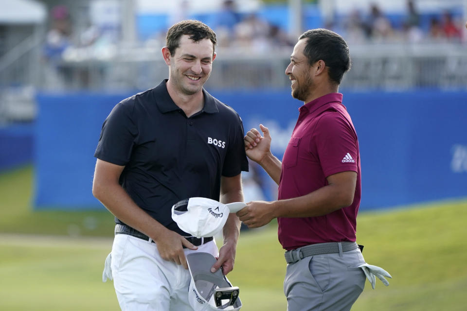 Patrick Cantlay greets teammate Xander Schauffele, right, on the 18th green after completing their third round of the PGA Zurich Classic golf tournament, Saturday, April 23, 2022, at TPC Louisiana in Avondale, La. (AP Photo/Gerald Herbert)