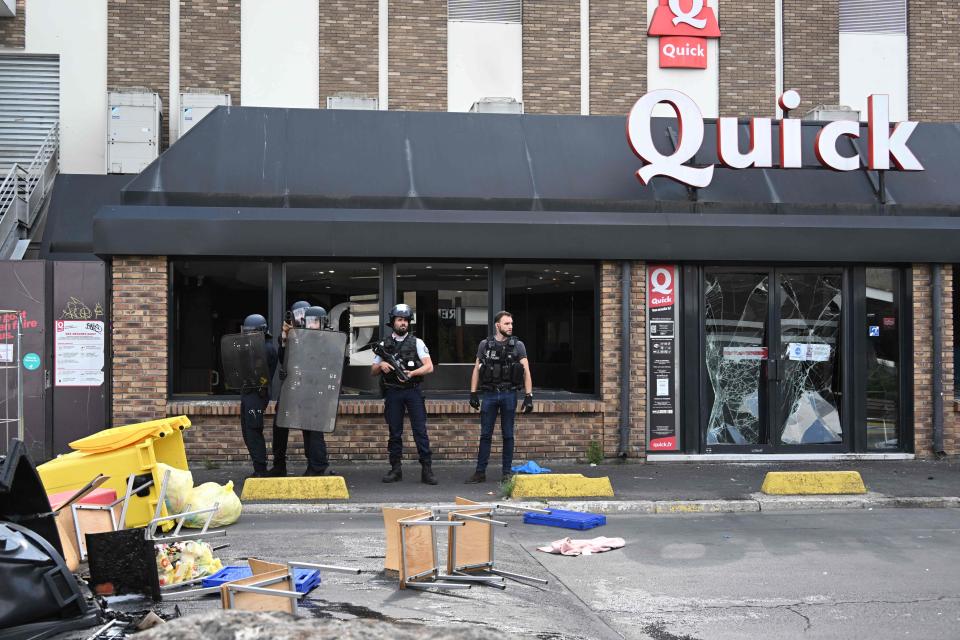 Police officers stand guard in front a fast food restaurant (AFP via Getty Images)