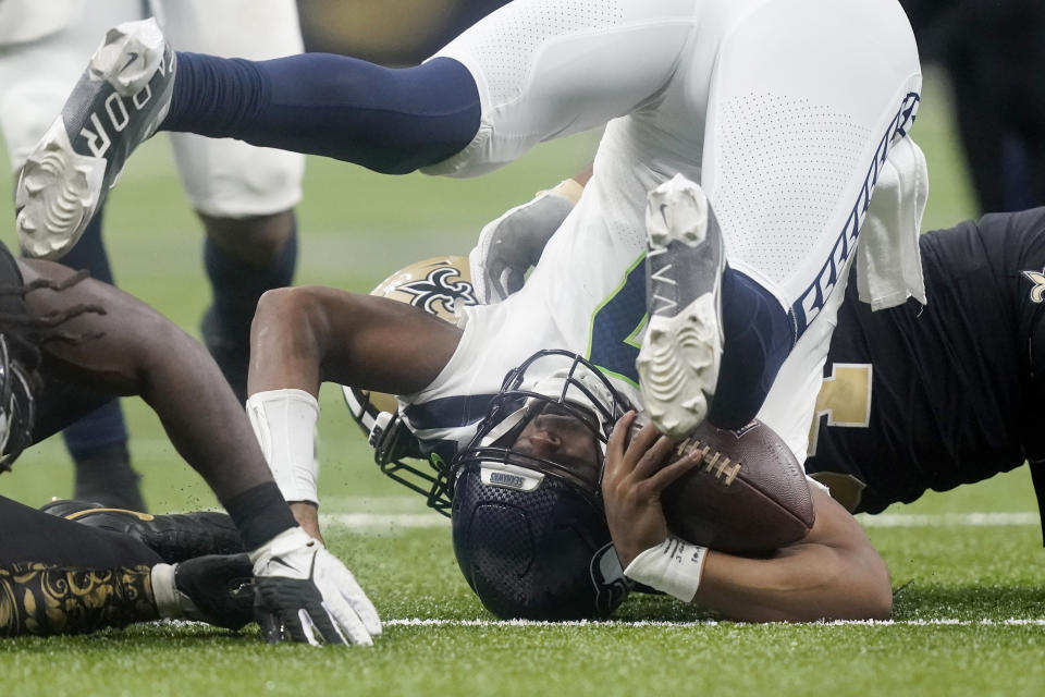 Seattle Seahawks quarterback Geno Smith is turned upside down after being sacked by New Orleans Saints defensive end Cameron Jordan, background, during an NFL football game in New Orleans, Sunday, Oct. 9, 2022. (AP Photo/Gerald Herbert)