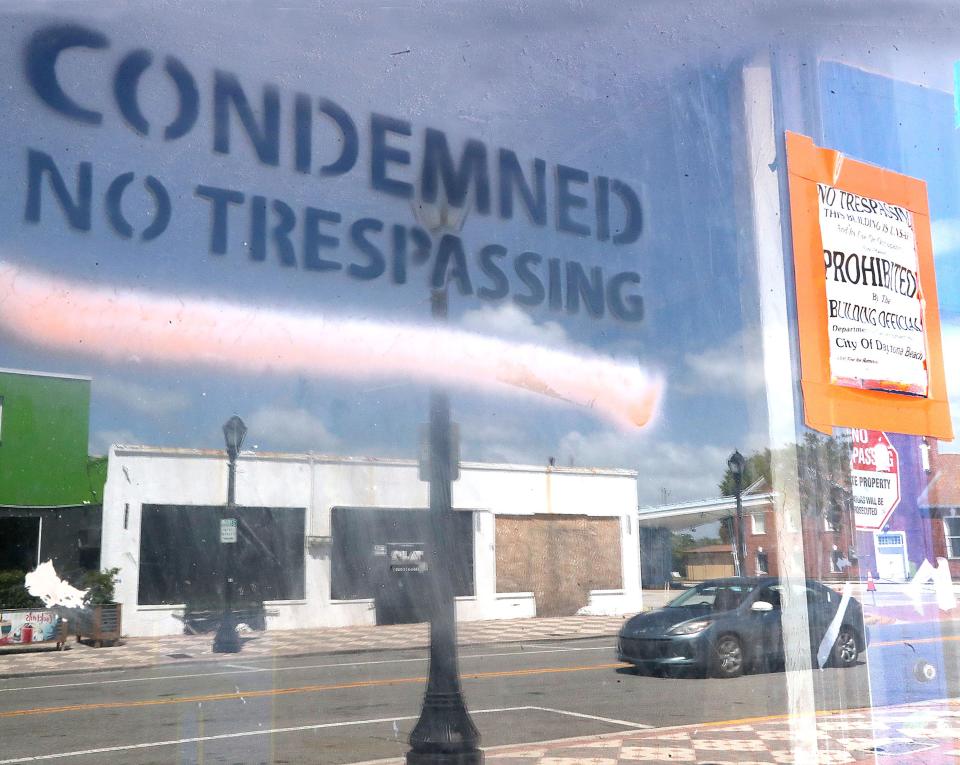 A boarded up business is reflected in the window of another boarded up business thats condemned and marked no trespassing, Monday April 29,2024 in the 500 block of Mary McLeod Bethune Blvd..