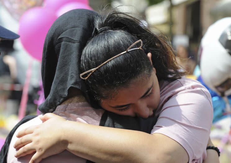 People comfort each other amid the tributes to the victims (Rex)