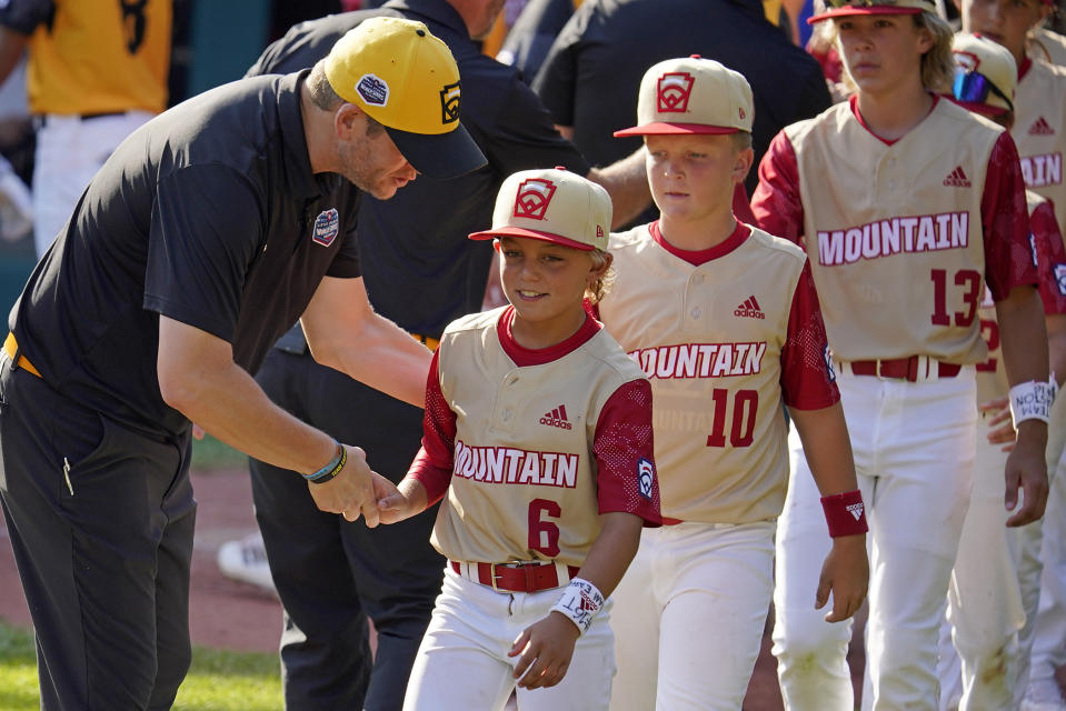 Santa Clara, Utah's Brogan Oliverson (6) shakes hands with Nolensville, Tenn., manager Randy Huth at the end of a baseball game at the Little League World Series in South Williamsport, Pa., Friday, Aug. 19, 2022. Tennessee won 11-2. (AP Photo/Gene J. Puskar)