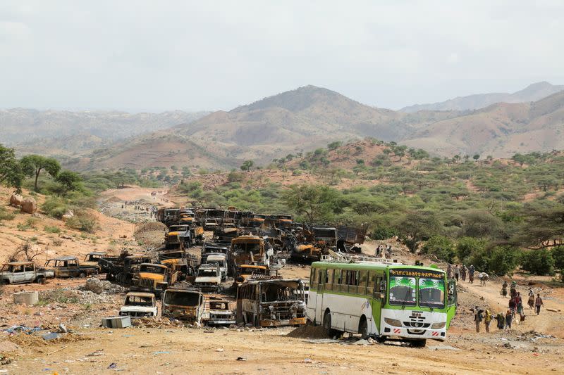 FILE PHOTO: Villagers return from a market to Yechila town in south central Tigray walking past scores of burned vehicles, in Tigray