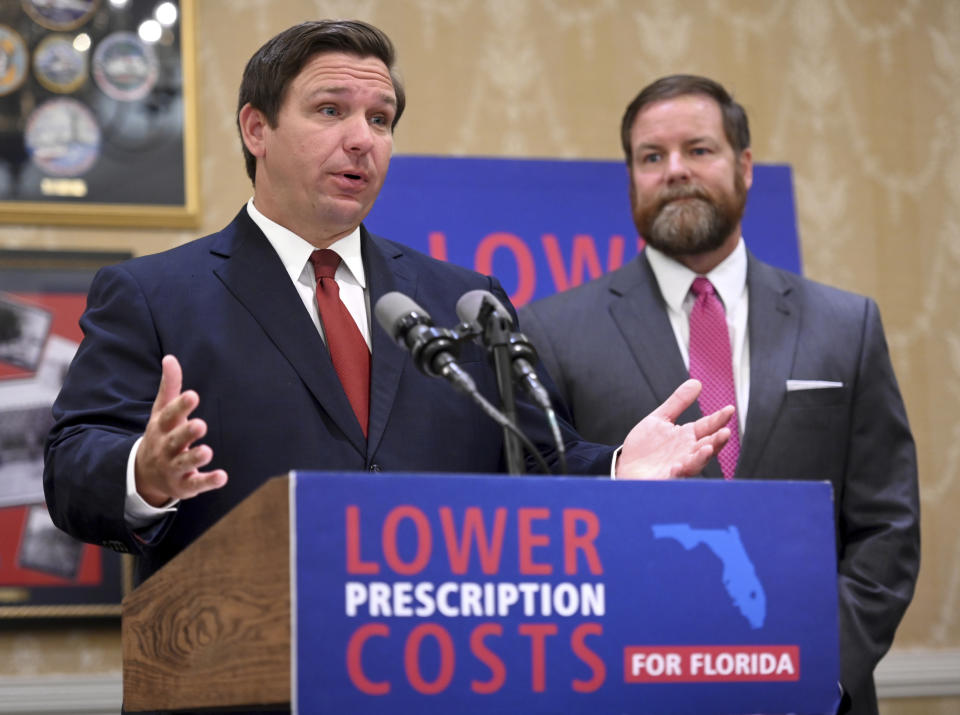 Florida Gov. Ron DeSantis speaks about the need to lower prescription costs by importing drugs from other countries, Tuesday, June 11, 2019, at the Eisenhower Recreation Center in The Villages, Fla. Listening at right is state Sen. Aaron Bean. (Max Gersh/Daily Sun via AP)