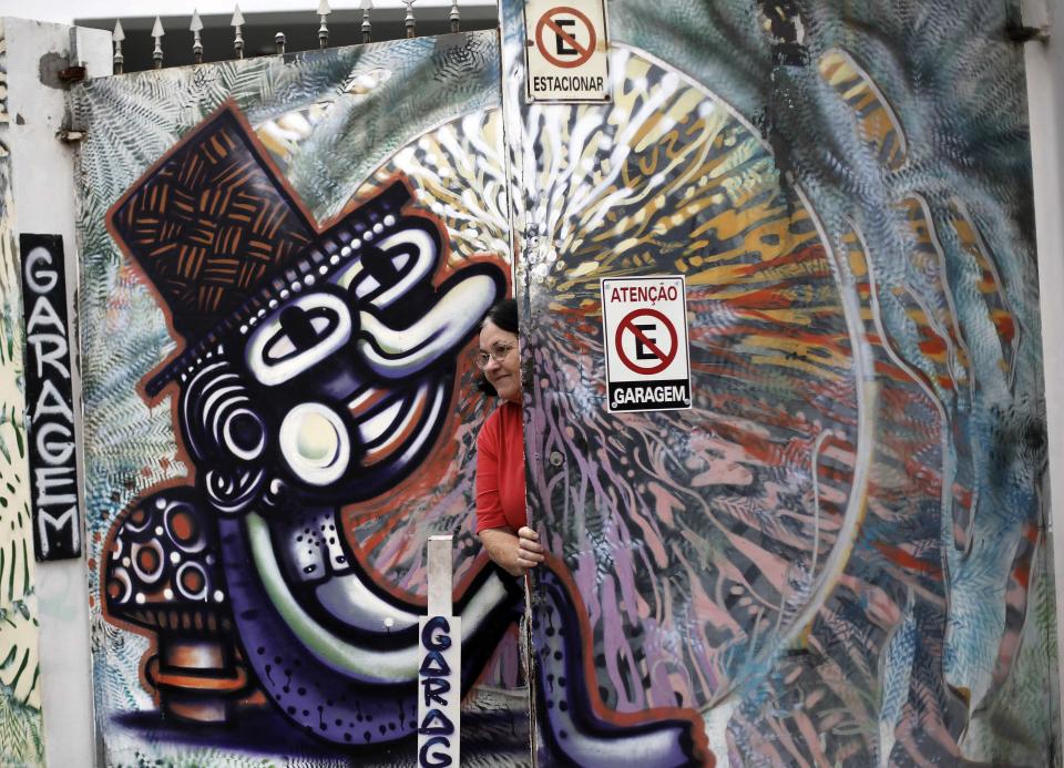 A woman closes the door garage of her house between graffiti-filled walls along "Beco do Batman" (Batman's alley) in the Vila Madalena neighbourhood, which is a well-known open-air graffiti museum, in Sao Paulo April 20, 2014. Sao Paulo is one of the host cities for the 2014 World Cup soccer matches in Brazil. REUTERS/Nacho Doce (BRAZIL - Tags: SPORT SOCCER WORLD CUP TRAVEL SOCIETY)