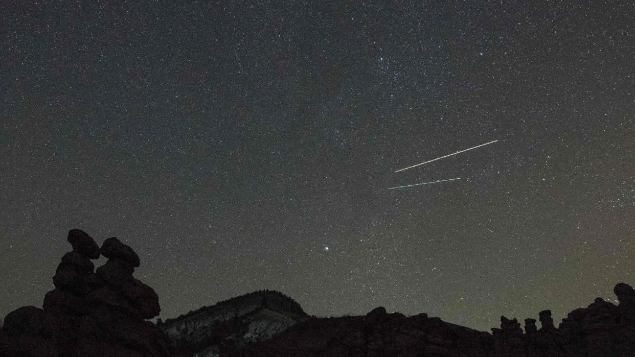  Several meteors can be seen streaking across a starry night sky. 