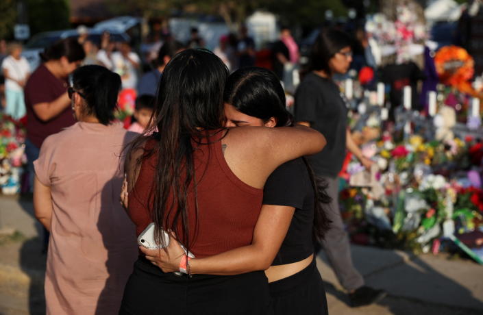 Women embrace at a memorial at Robb Elementary School in Uvalde, Texas, where a gunman killed 19 children and two teachers. 