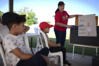 La maestra de kindergarten Nydsy Santiago da una clase en la glorieta de un parque deportivo municipal el 4 de febrero del 2020 en Santa Isabel, Puerto Rico. La escuela a la que van los niños, la Martin G. Brumbaugh, está cerrada desde el terremoto que azotó el sur de la isla en enero. (AP Photo/Carlos Giusti)