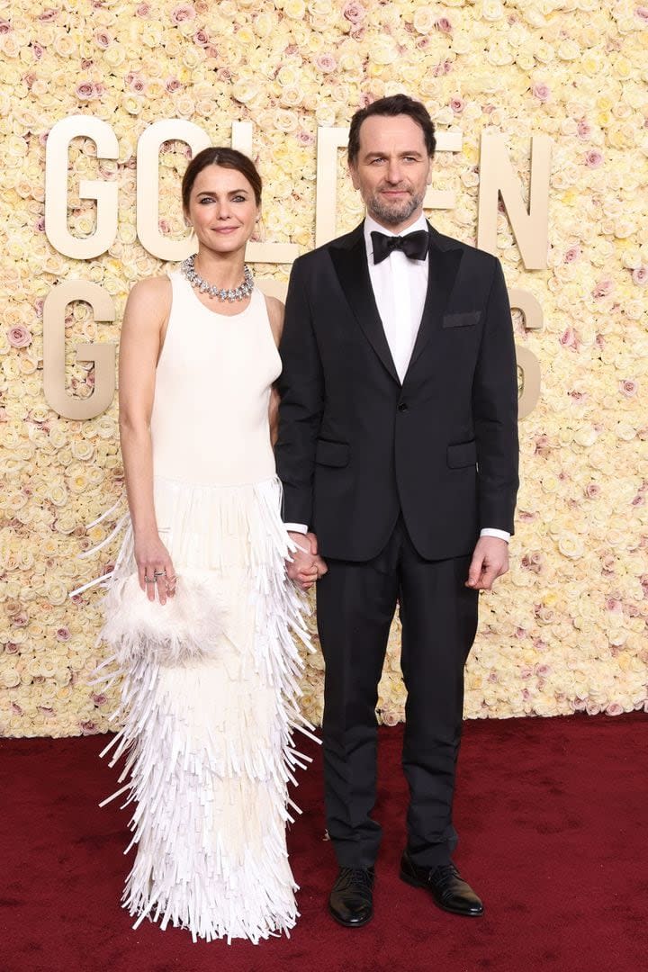 Keri Russell posó junto a su marido, el también actor Matthew Rhys. La intérprete, nominada por su trabajo en La diplomática, eligió un vestido largo tubo en color blanco con flecos y un clutch de plumas a tono