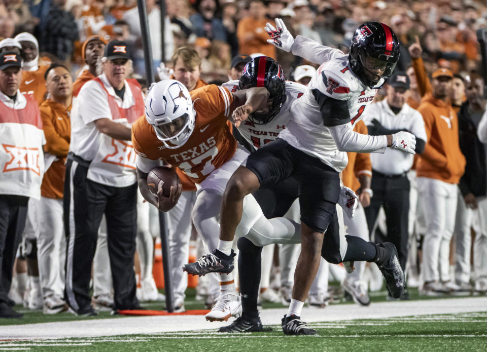 Texas Tech defenders Dadrion Taylor-Demerson, right, and lBen Roberts, center, tackle Texas running back Savion Red during the second half of an NCAA college football game Friday, Nov. 24, 2023, in Austin, Texas. (AP Photo/Michael Thomas)