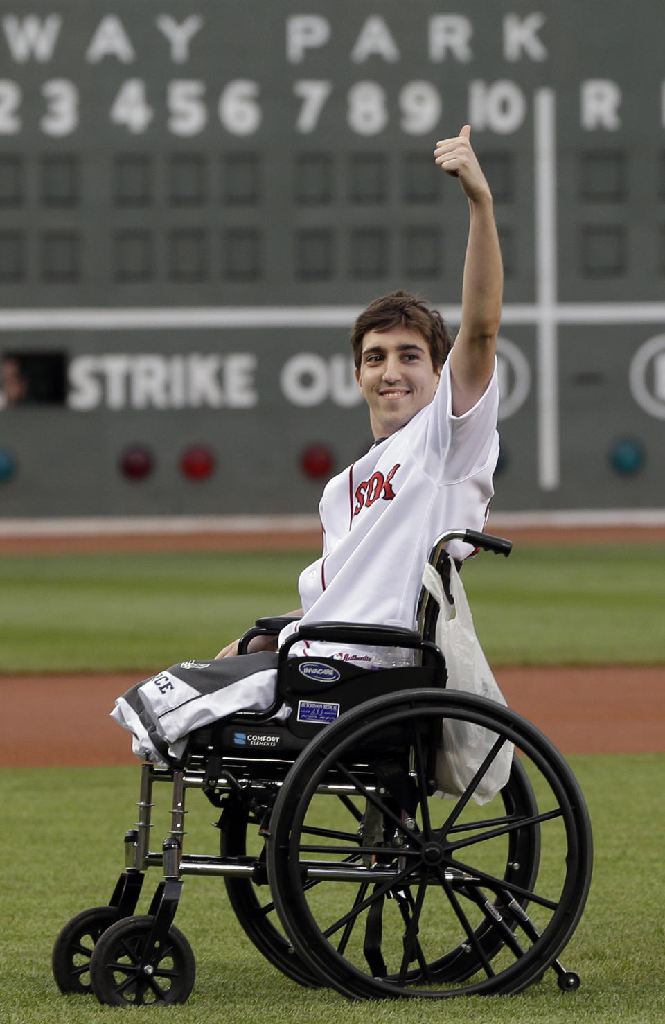 This May 28, 2013 file photo, Boston Marathon bombing survivor Jeff Bauman acknowledges cheering fans before throwing out a ceremonial first pitch at Fenway Park prior to a baseball between the Boston Red Sox and the Philadelphia Phillies in Boston. Bauman, who lost both legs in the Boston Marathon bombings, then helped authorities identify the suspects, is engaged and an expectant father. Bauman and his fiancé, Erin Hurley, tell The Associated Press that the baby is due July 14. They don’t know if it’s a boy or a girl, and they want it to be a surprise. The two were engaged in February. (AP Photo/Elise Amendola)