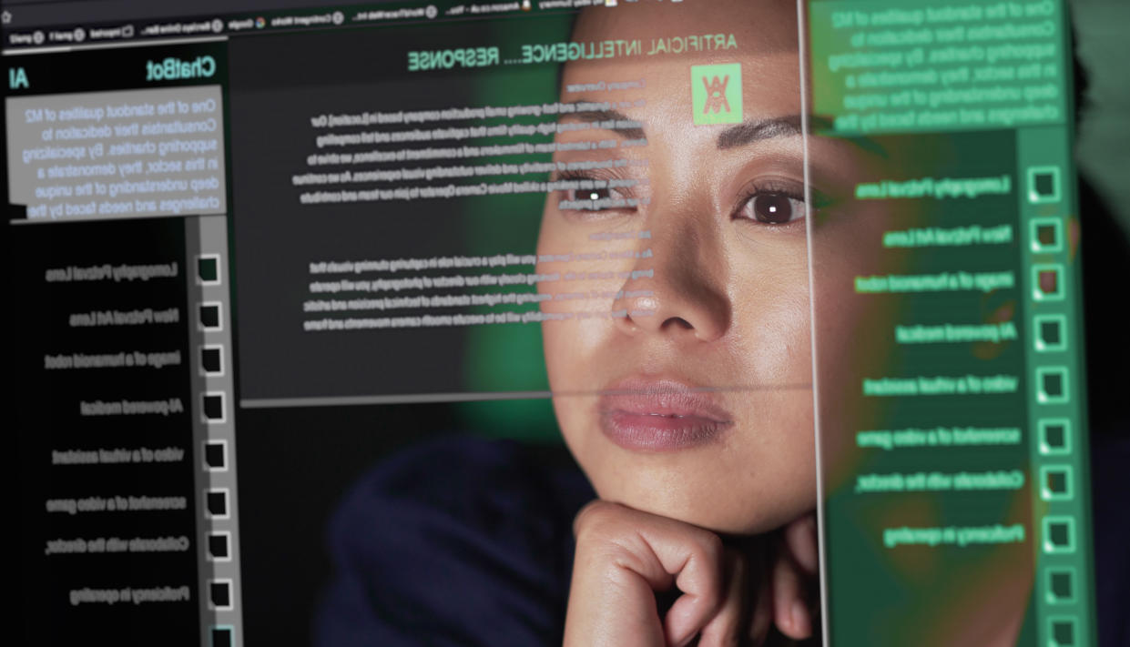 Stock image showing an Asian woman studying a see through screen which is producing lines of AI generated text. A ChatBot similar to ChatGPT is being read attentively by this woman.
