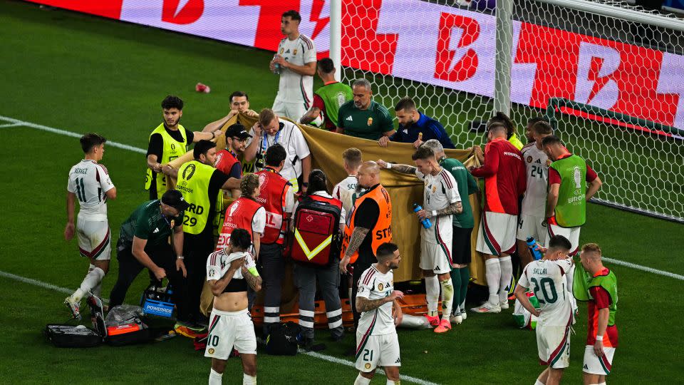 Players and stewards hold sheets to hide Varga while he receives medical treatment. - Damien Meyer/AFP/Getty Images