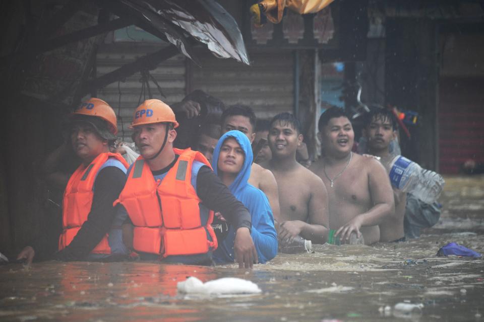 Rescuers (front L) guide residents with their belongings as they evacuate from their flooded homes in Tumana village, Marikina City, east of Manila (AFP via Getty Images)