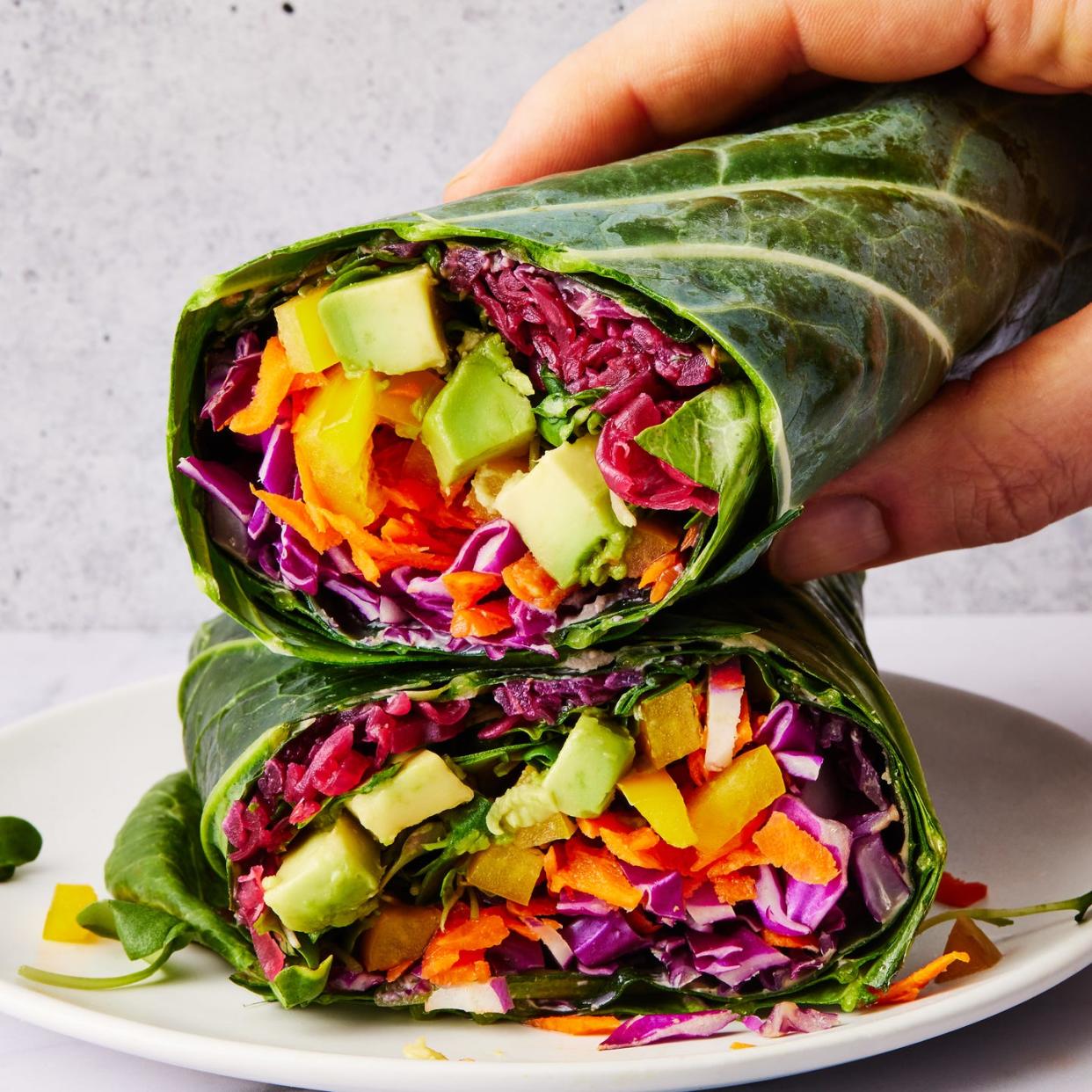 collard green wrap filled with shredded purple cabbage, grated carrots, yellow bell pepper, avocado, alfalfa sprouts and red sauerkraut