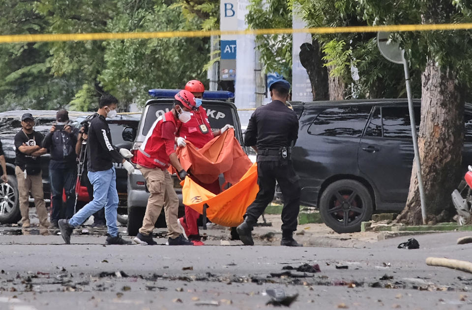 Police officer and rescue workers carry a body bag containing what is believed to be human remains outside a church where an explosion went off in Makassar, South Sulawesi, Indonesia, Sunday, March 28, 2021. A suicide bomber blew himself up outside a packed Roman Catholic cathedral on Indonesia's Sulawesi island during a Palm Sunday Mass, wounding a number of people, police said. (AP Photo/Masyudi S. Firmansyah)