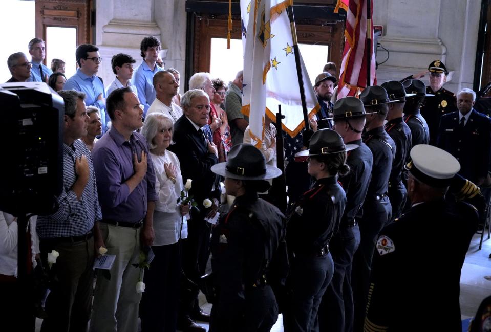 Family members of those Rhode Islanders who died on 9/11 stand as the RI State Police color guard helps open the Sunday morning ceremony at the State House.