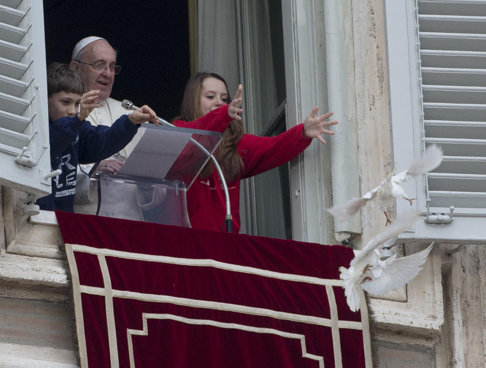 Pope Francis looks at two children as they free doves during the Angelus prayer he celebrated from the window of his studio overlooking St. Peter's Square, at the Vatican, Sunday, Jan. 26, 2014. Pope Francis has called for "constructive dialogue" between Ukraine's authorities and its people, urging all to renounce violence in the upheaval convulsing their country. Speaking from a window of the Apostolic Palace in the Vatican to thousands of faithful in St. Peter's Square, Francis said he was praying for Ukraine, especially for those who have lost their lives in recent days. He appealed on Sunday for "the spirit of peace and the search for the common good" to prevail in the eastern European nation. (AP Photo/Gregorio Borgia)